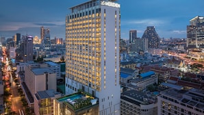 A high-rise hotel with a grid of windows, surrounded by a cityscape at dusk. - Le Meridien Bangkok (Bangkok)