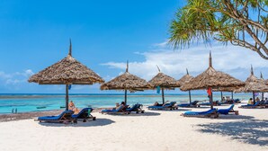 A beach with thatched umbrellas and sun loungers. - Southern Palms Beach Resort (Diani Beach)