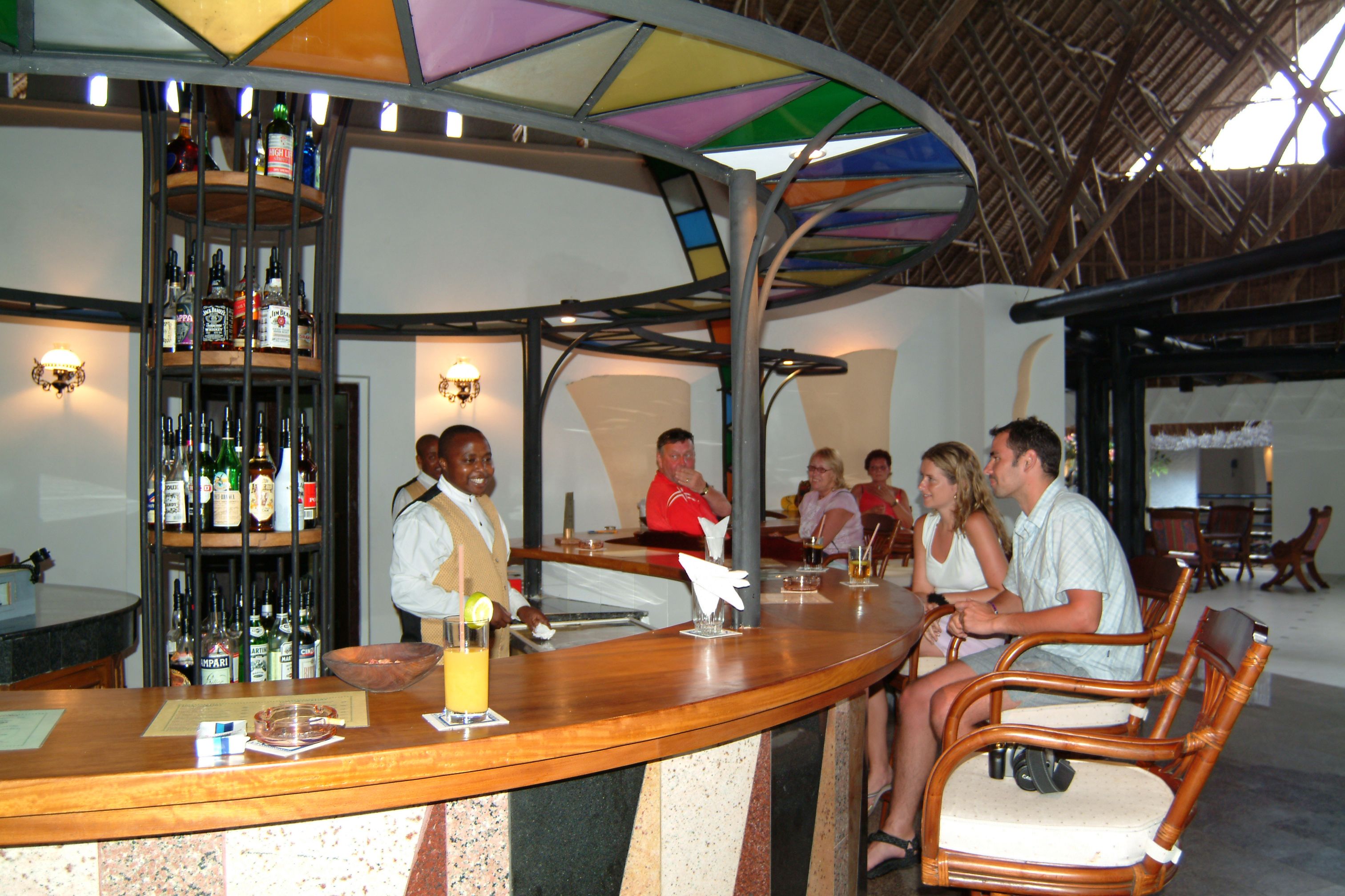A bar area with a wooden counter, bar stools, and a wall-mounted liquor display.