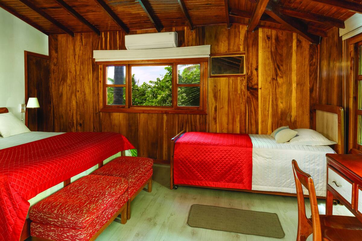 Una habitación de madera con dos camas, un banco y un escritorio.