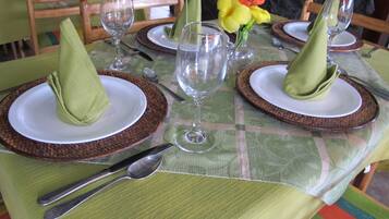 Una mesa de comedor puesta con servilletas verdes, platos blancos y cristalería transparente.