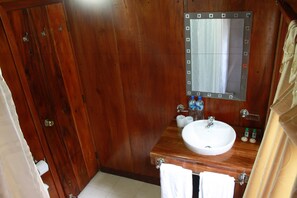 A wooden bathroom with a sink, mirror, and towel rack.