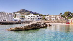 Un pueblo costero con aguas cristalinas, afloramientos rocosos y edificios con balcones que dan al mar.