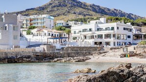 Un pueblo costero con edificios modernos, un litoral rocoso y una montaña al fondo.