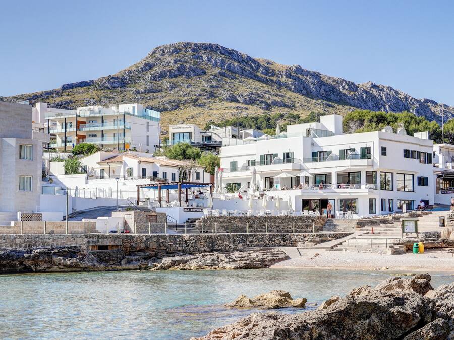 Une ville côtière dotée de bâtiments modernes, d’un littoral rocheux et d’une montagne en arrière-plan.