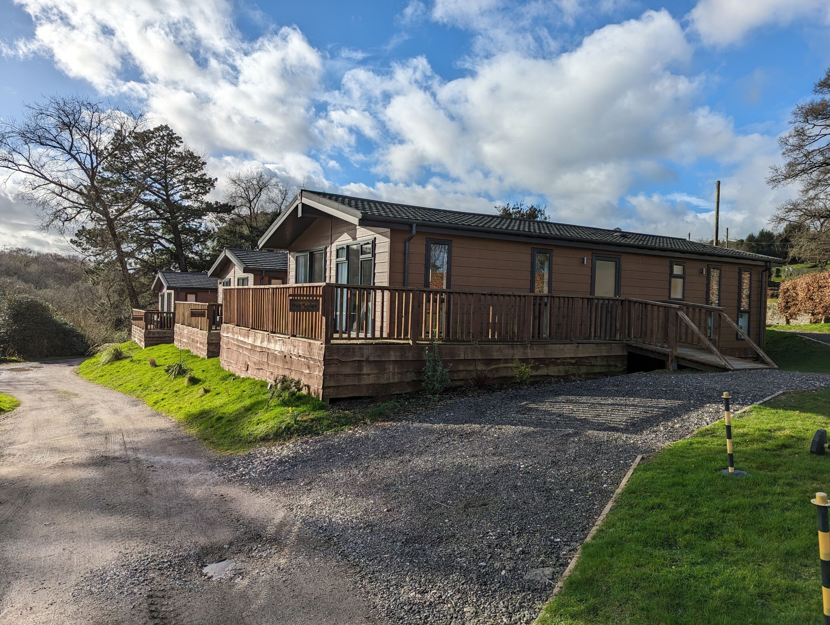 A lodge with a wooden deck, a gravel driveway, and a clear sky.