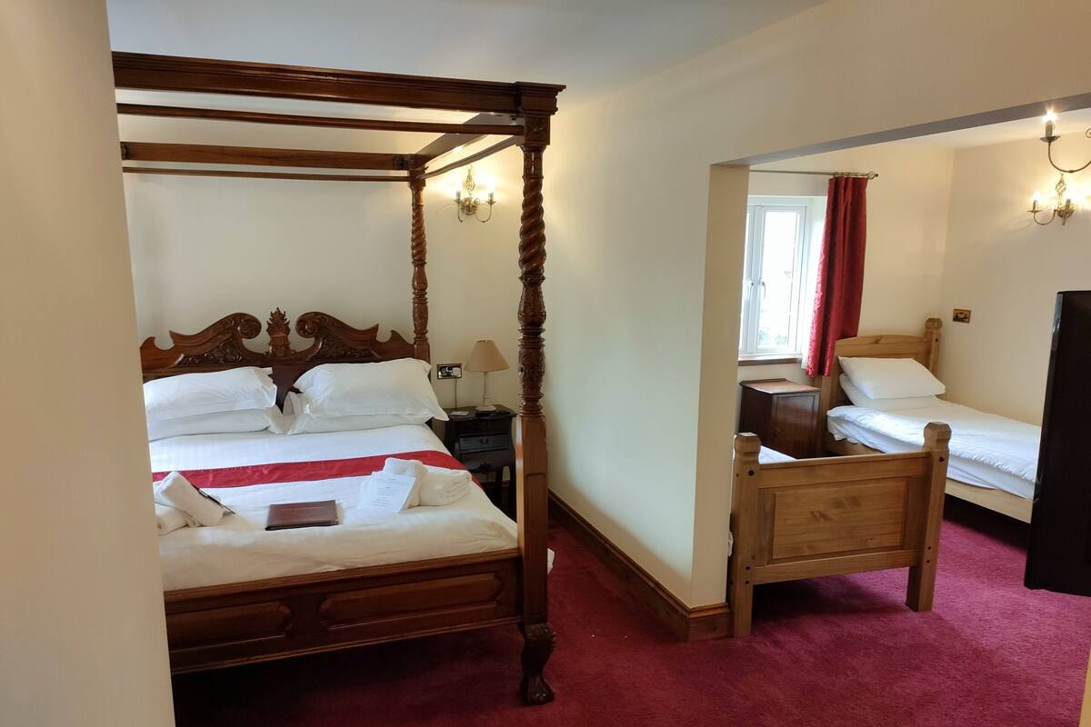 A four-poster bed with a wooden frame and a red carpeted floor.
