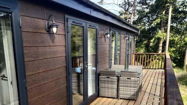 Une terrasse en bois avec des portes vitrées et du mobilier d’extérieur.