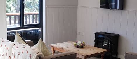 A spacious living room with a sofa, a wooden coffee table, and a television mounted on the wall.