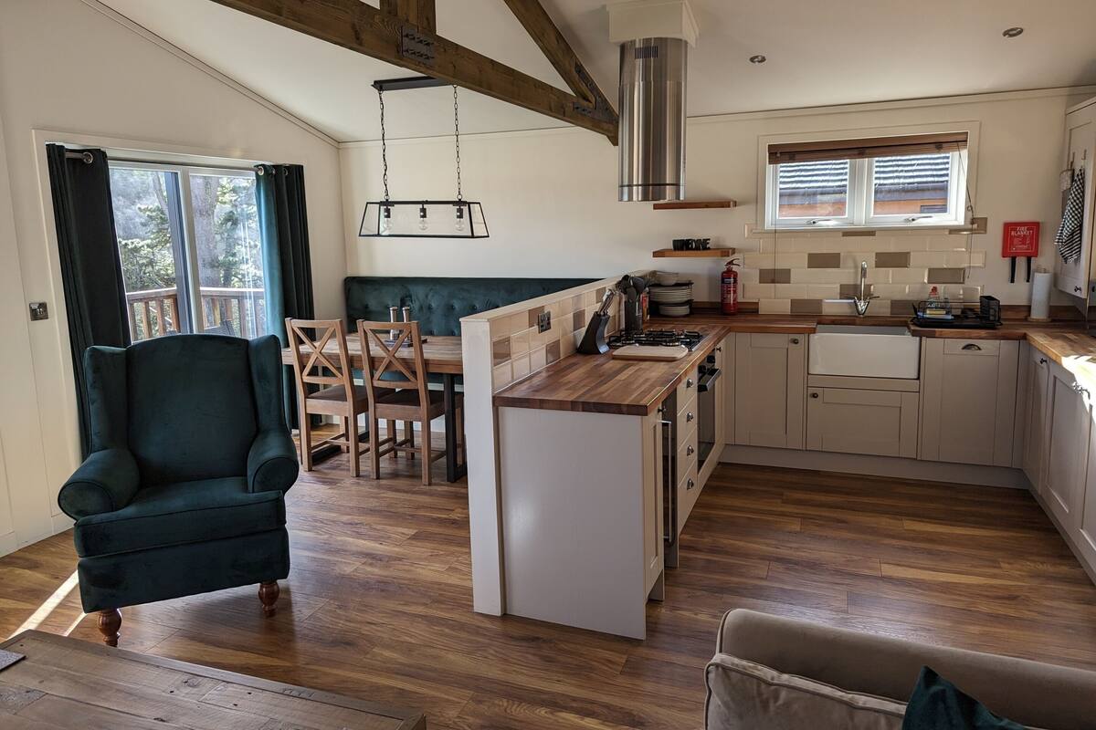 A modern kitchen with wooden countertops, a built-in stove, and a dining area with a green upholstered bench.