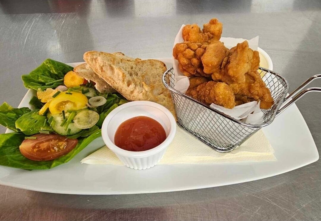 Un piatto con insalata, pane e fritture.
