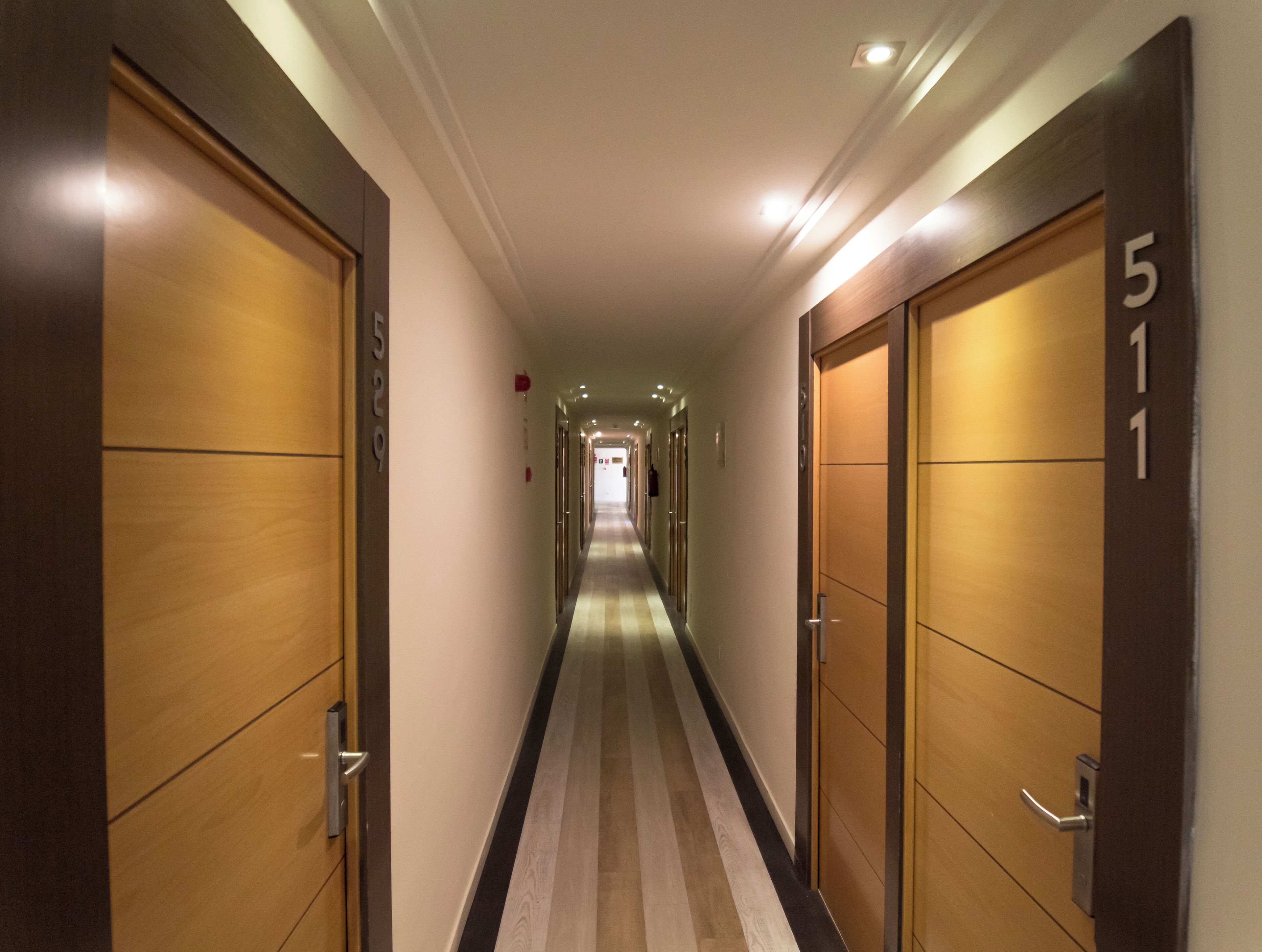 Pasillo de hotel con puertas de madera, números 511 y 529, y piso a rayas.
