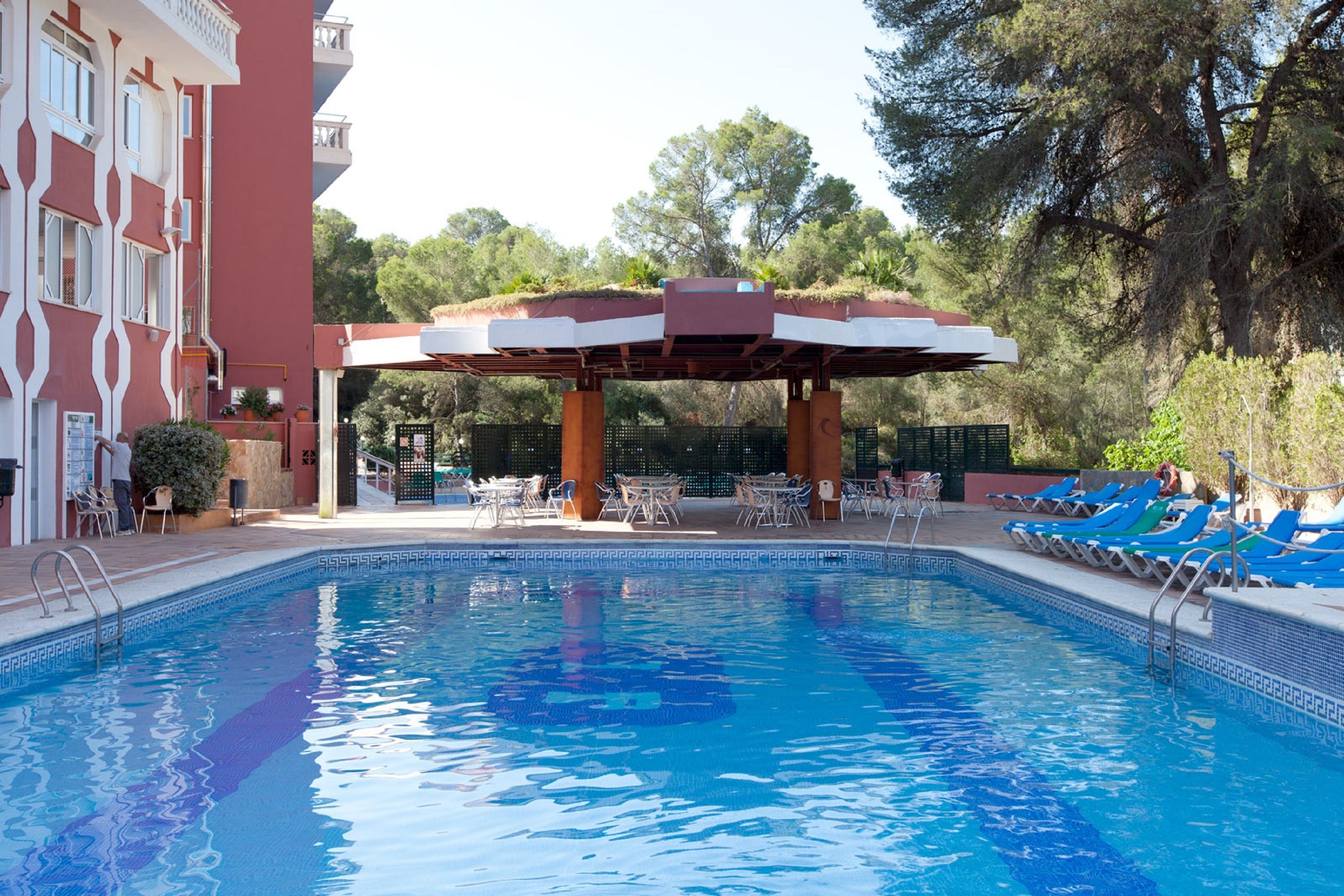 A swimming pool with lounge chairs and a covered seating area.