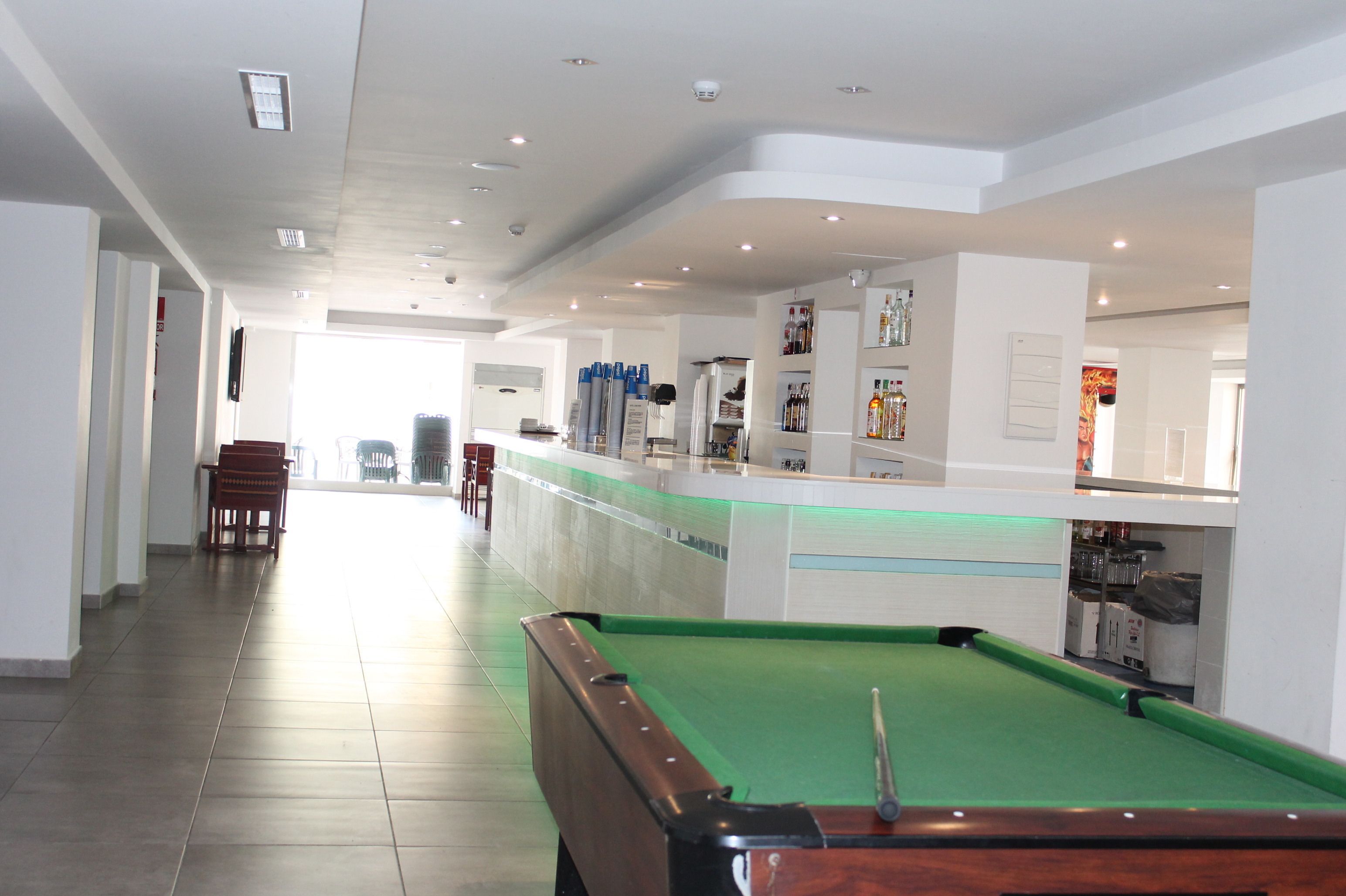 A pool table in a hotel lobby with a bar area and seating.