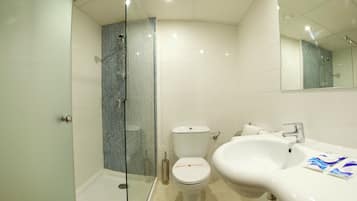 Een moderne badkamer met een douche in een glazen cabine, een wit toilet en een groot wastafelmeubel met een spiegel erboven.