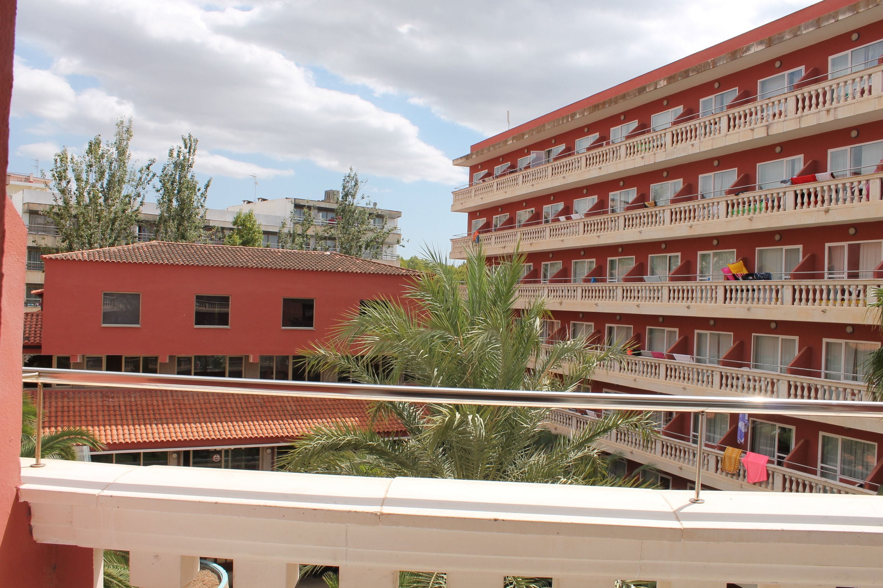 A multi-story hotel with balconies and a red facade.