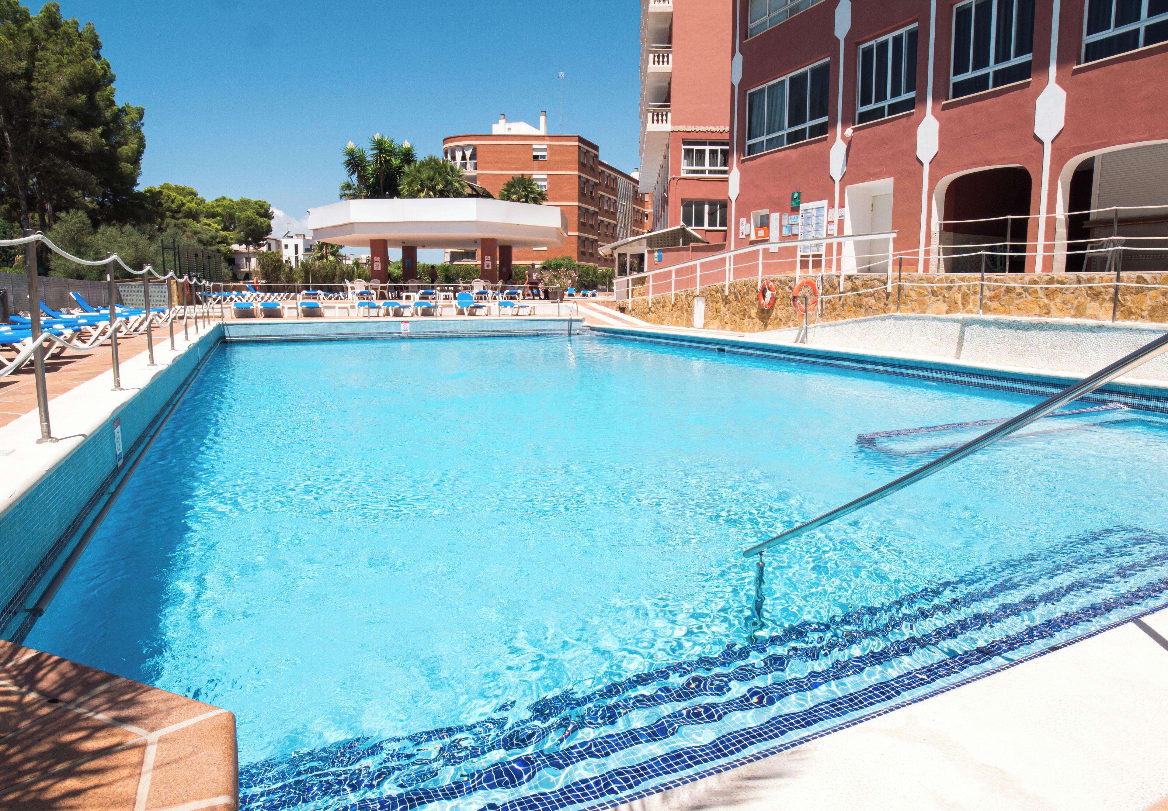 A swimming pool with lounge chairs and a building in the background.