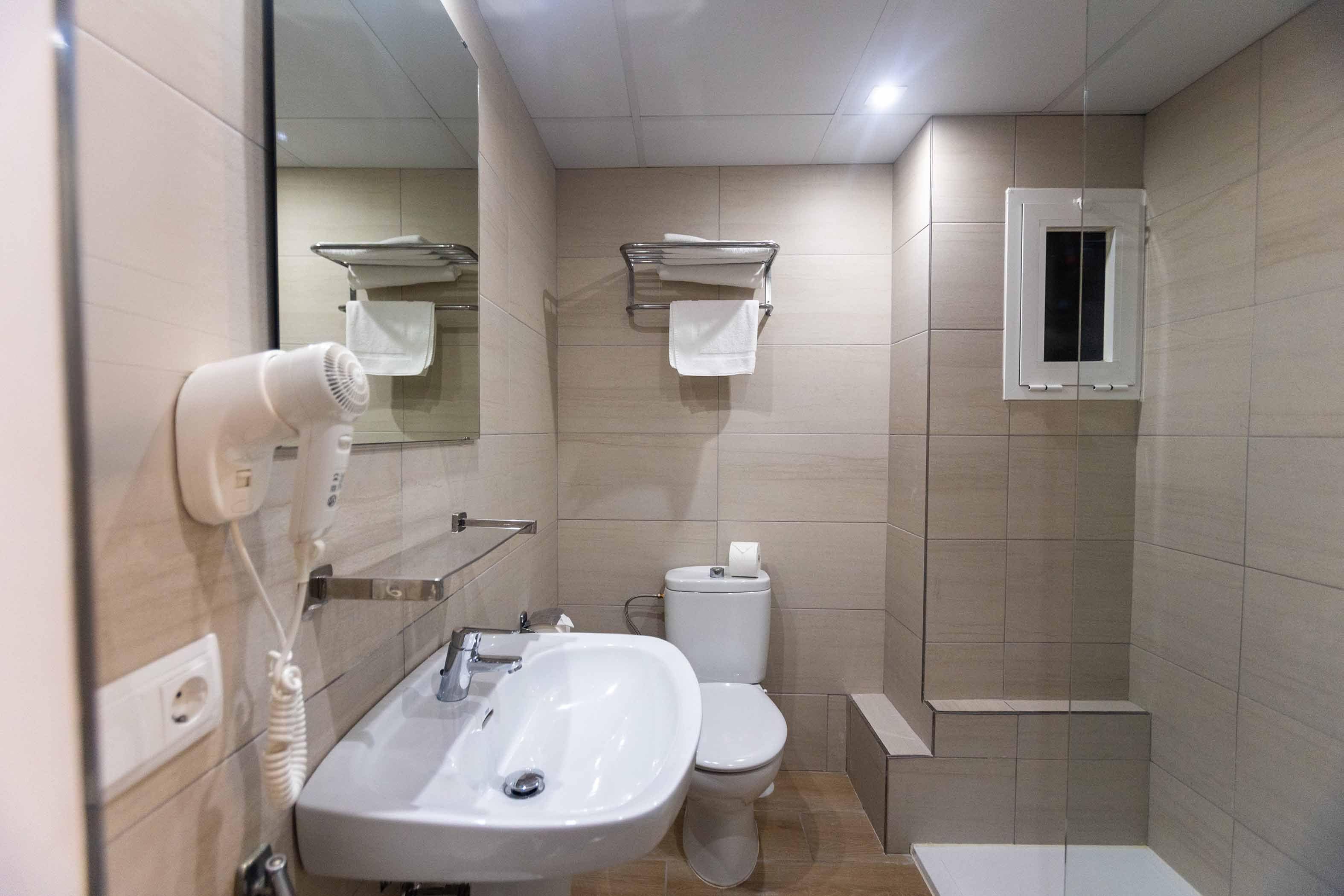 Un baño con lavamanos, inodoro y espejo.