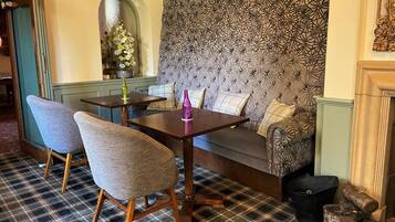 A cozy seating area with a patterned sofa, two upholstered chairs, and a small table with decorative bottles.
