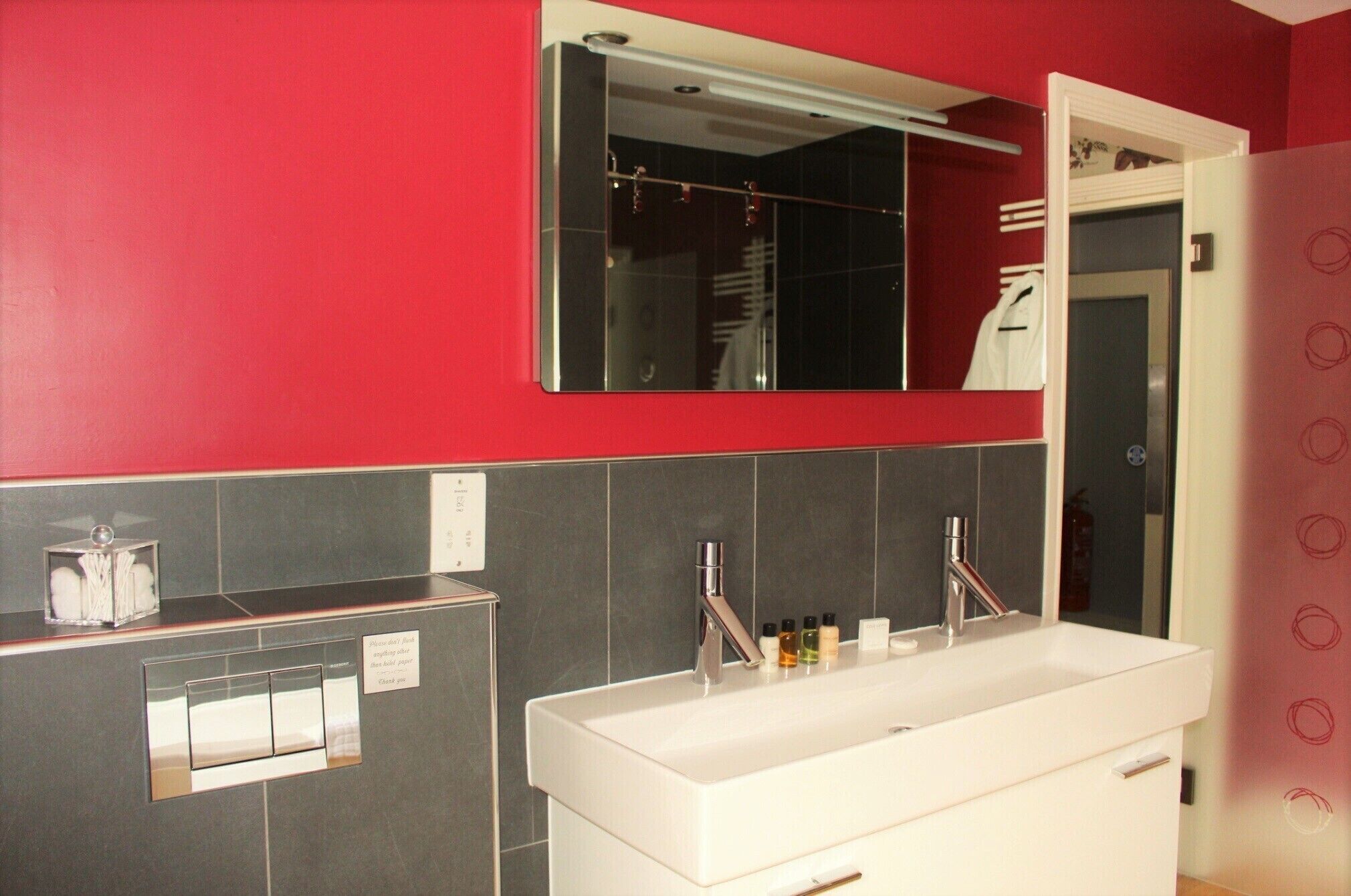 A modern bathroom with a large mirror, two sinks, and a towel rack.
