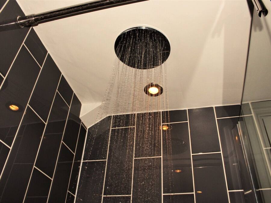 A shower with a circular drain and water falling into it.