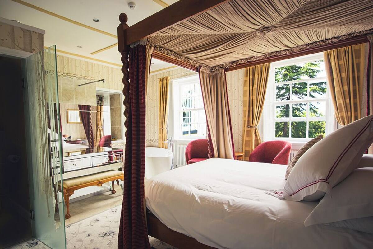 A four-poster canopy bed with a mirror and a vanity in the room.