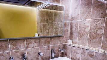 A modern bathroom with two sinks, a mirror, and a trash bin.