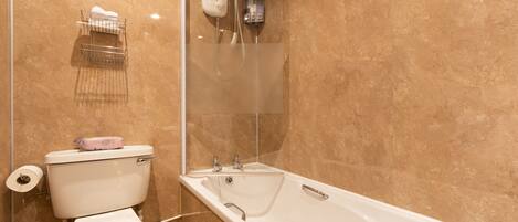 Un baño con inodoro, ducha con mampara de vidrio y bañera.