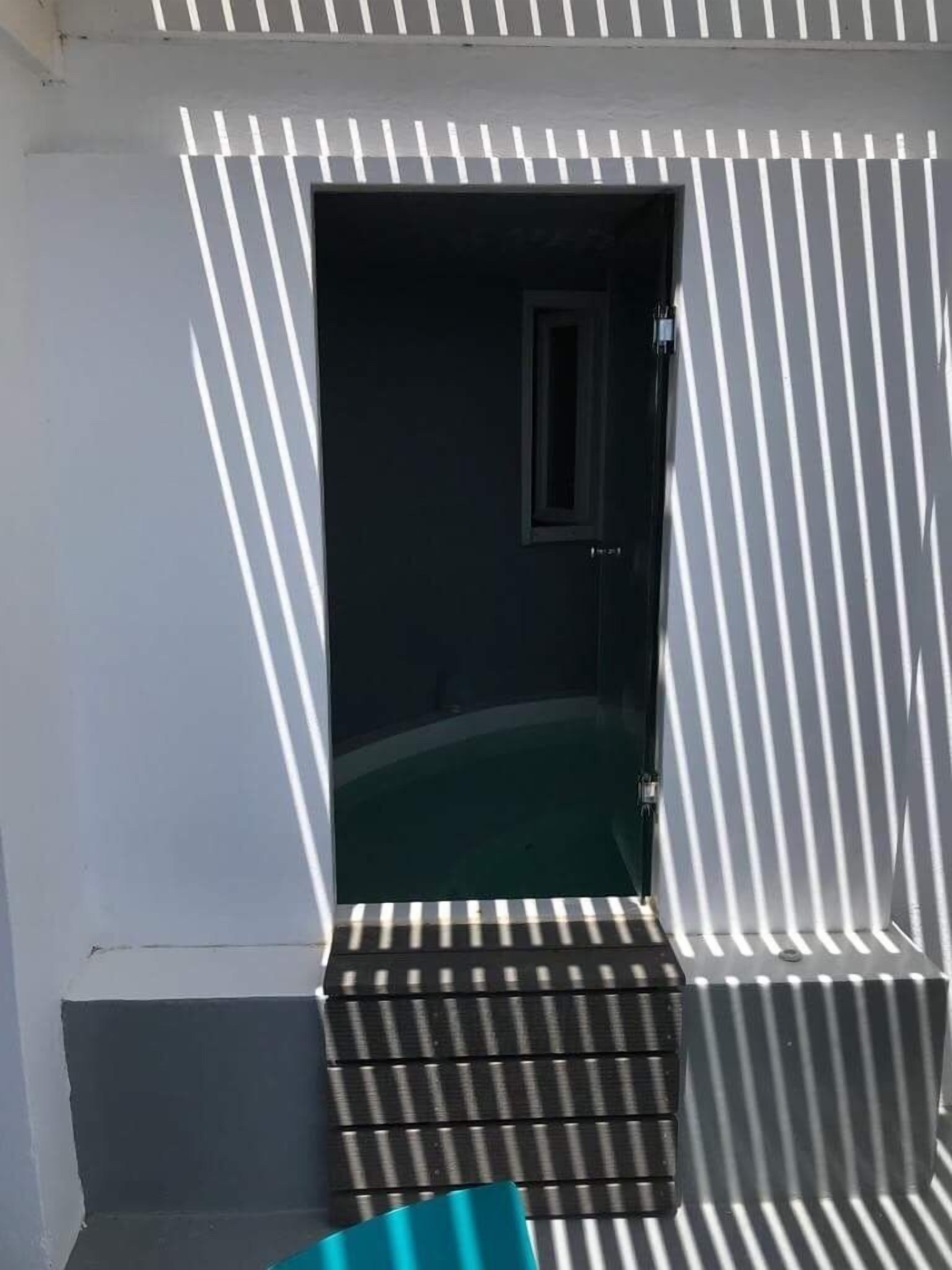 A room with a dark interior, a window, and a door.