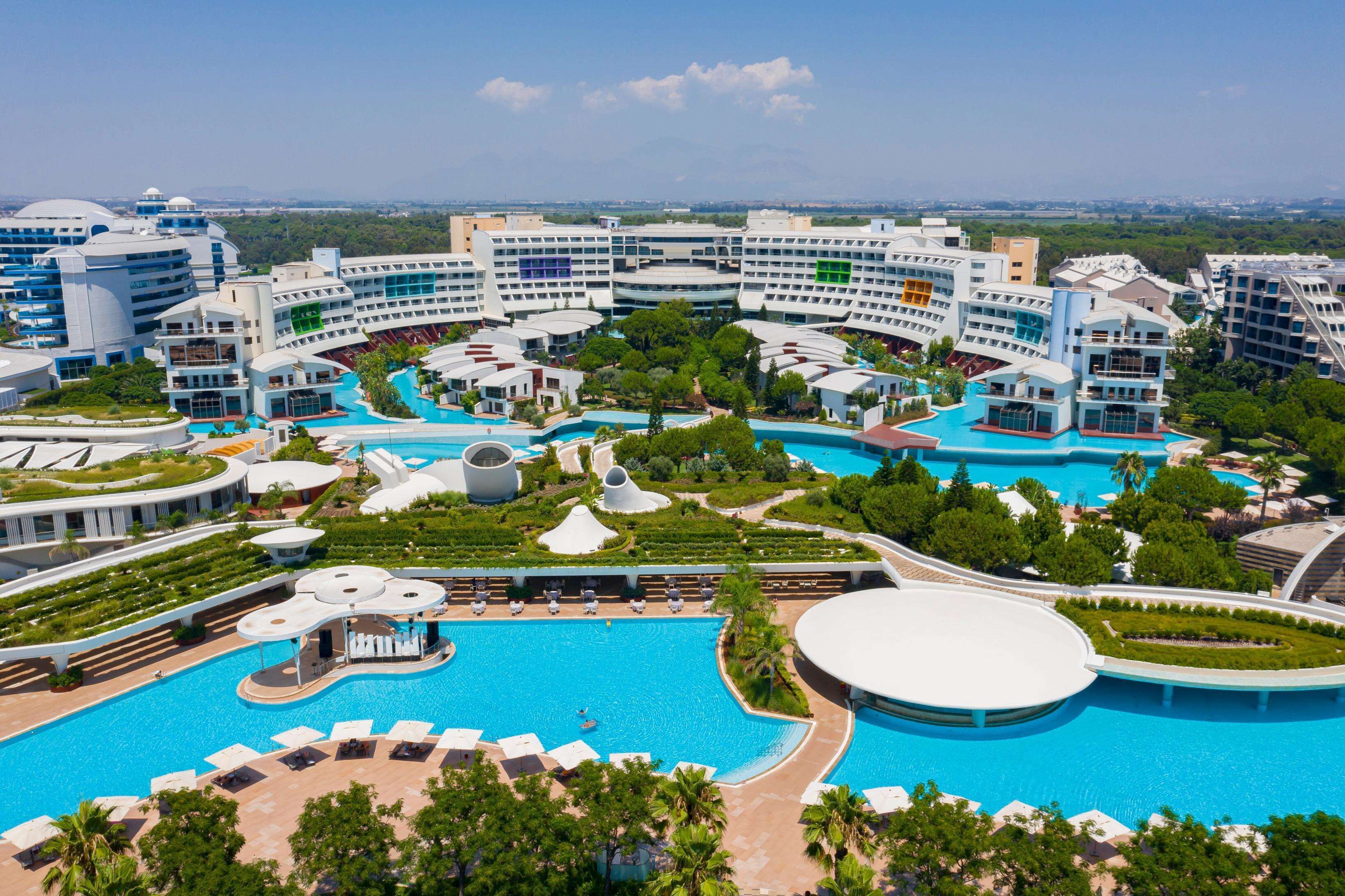 A resort with multiple swimming pools, lush greenery, and modern architecture.