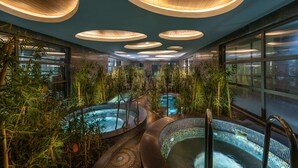 A spa area with multiple hot tubs surrounded by bamboo plants, under circular wooden ceiling lights. - Cornelia Diamond Golf Resort & SPA (Serik)