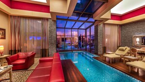 A hotel room with a pool, red furniture, and a view of the cityscape through large windows. - Cornelia Diamond Golf Resort & SPA (Serik)