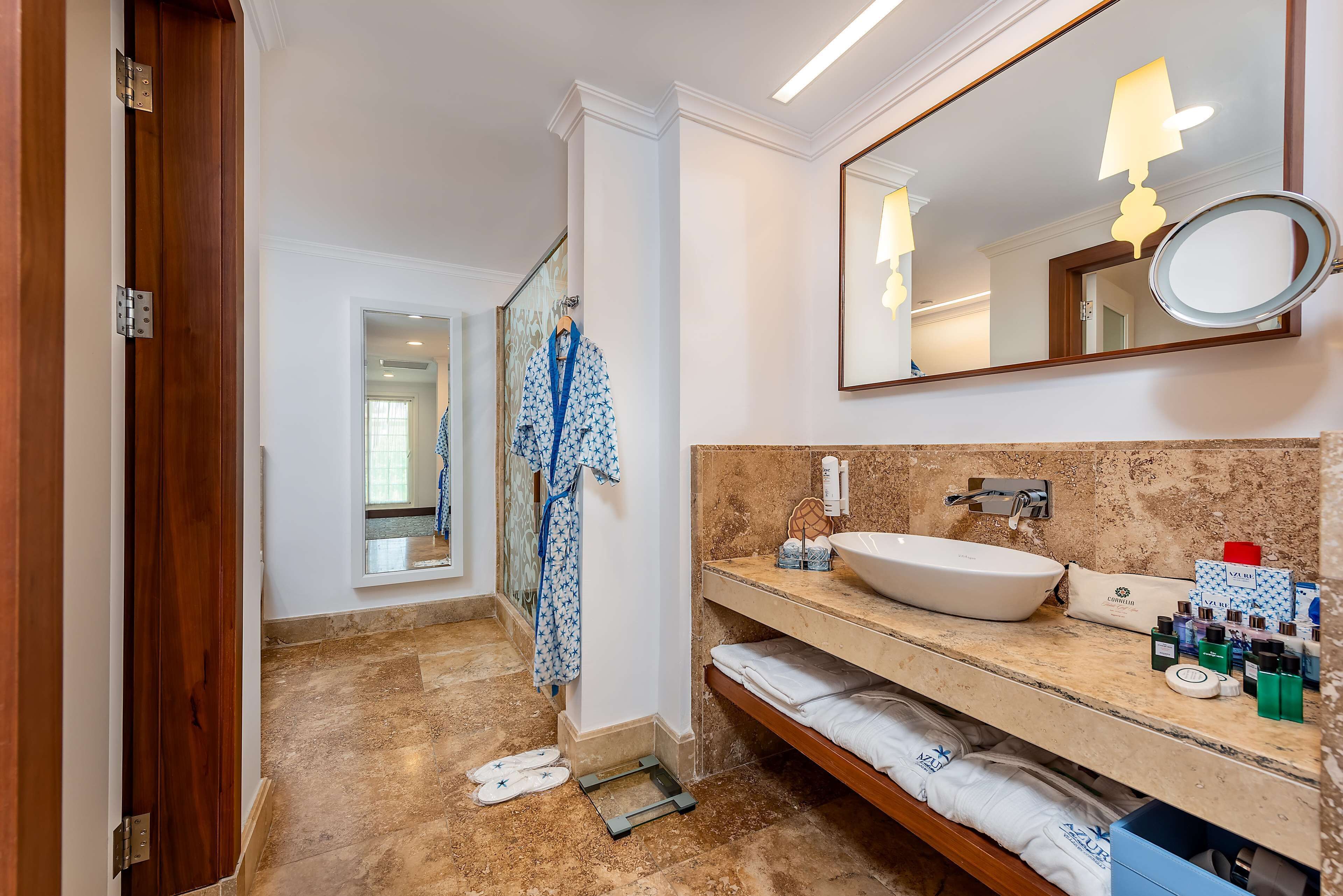 A bathroom with a large mirror, a sink, and a robe rack.