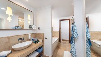 Un baño moderno con un espejo grande, un lavamanos, una bañera y una ducha.
