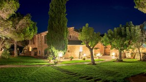 A stone building with a courtyard at night, illuminated by street lamps. - Sa Galera Hotel Rural (Felanitx)