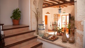 A staircase leading to a room with a rustic interior, featuring a wooden ceiling, a tiled floor, and a variety of potted plants and vases on the landing. - Sa Galera Hotel Rural (Felanitx)