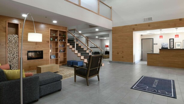 A spacious lobby with a staircase, a reception desk, and a seating area with a sofa and a chair. - Country Inn & Suites by Radisson, Oklahoma City Airport, OK (Oklahoma City)