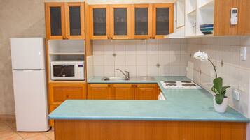 A kitchen with wooden cabinets, a white refrigerator, a microwave, a sink, and a stove.