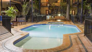 Une piscine intérieure au design incurvé, entourée d’une terrasse carrelée et de rampes en métal noir.