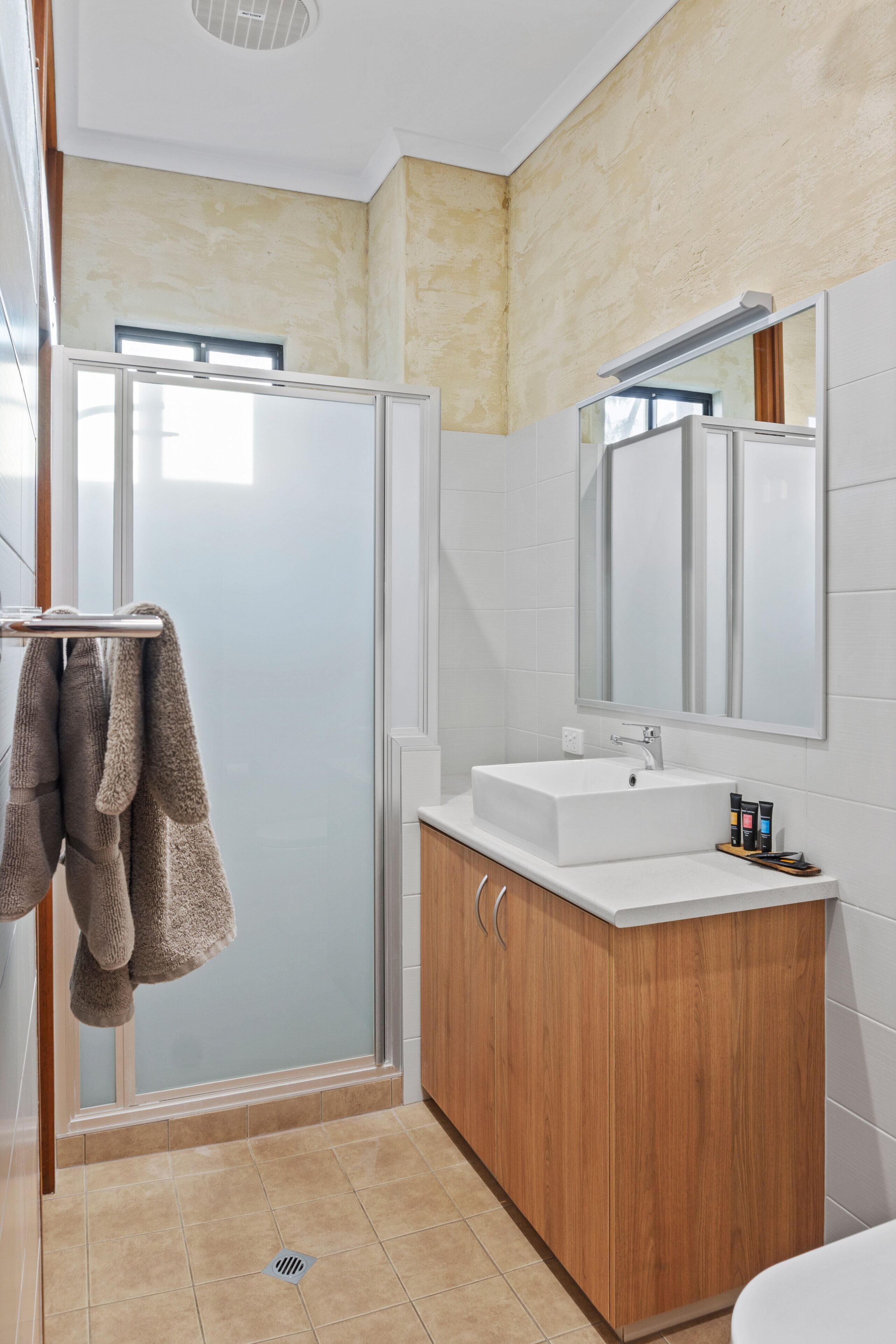 Une salle de bain moderne avec une douche à parois de verre, un meuble-lavabo en bois et un grand miroir.