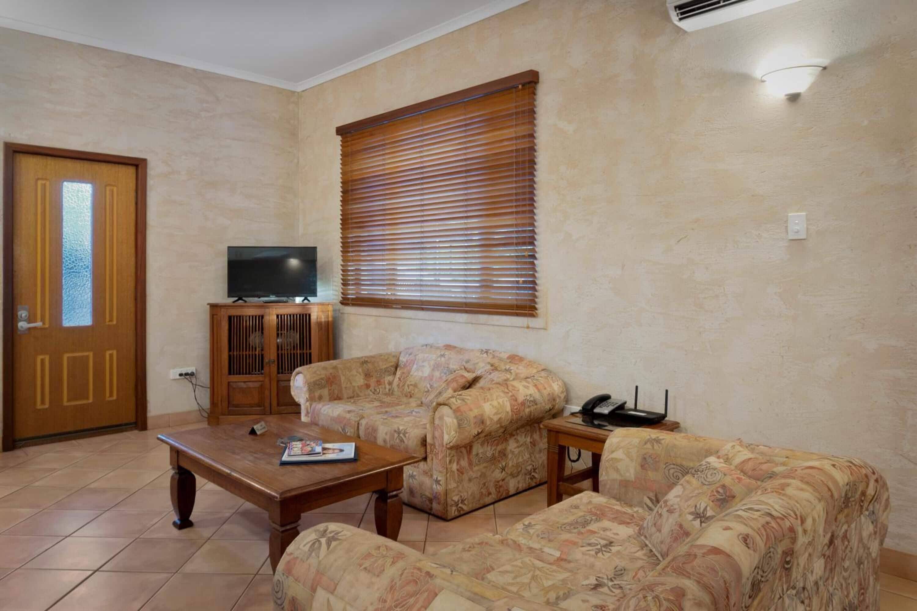 A living room with a sofa, a coffee table, a television, and a cabinet.