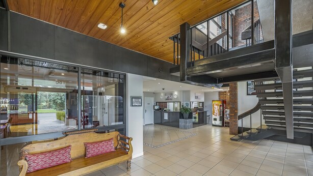 A spacious lobby with a wooden bench, a staircase, and a reception area.