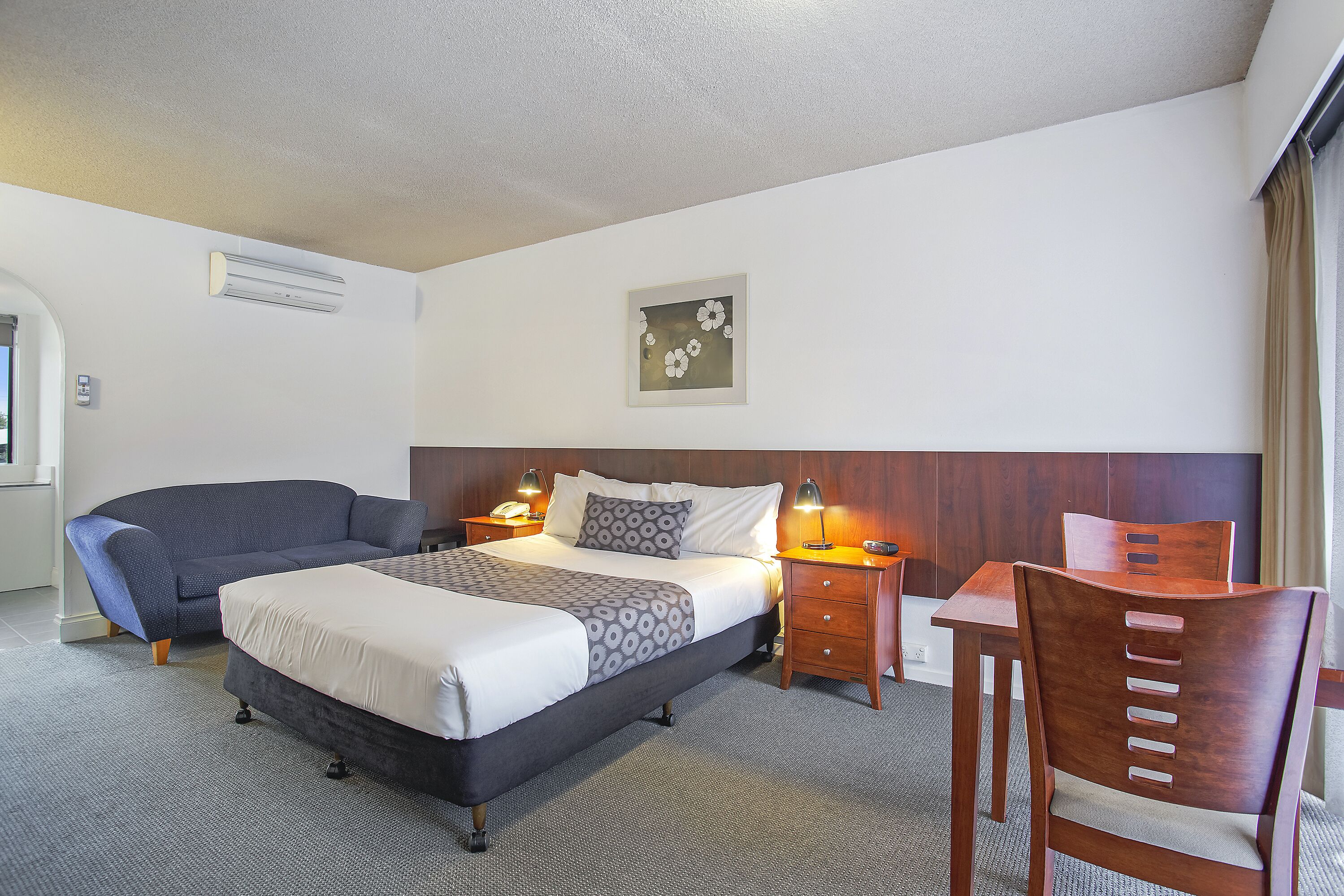 A hotel room with a bed, a sofa, a desk, and a chair.