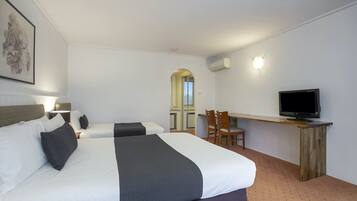 A hotel room with two beds, a desk with a TV, and a mirror.