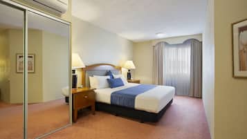 Habitación de hotel con una cama grande, dos mesitas de noche con lámparas, un espejo y una puerta corredera.