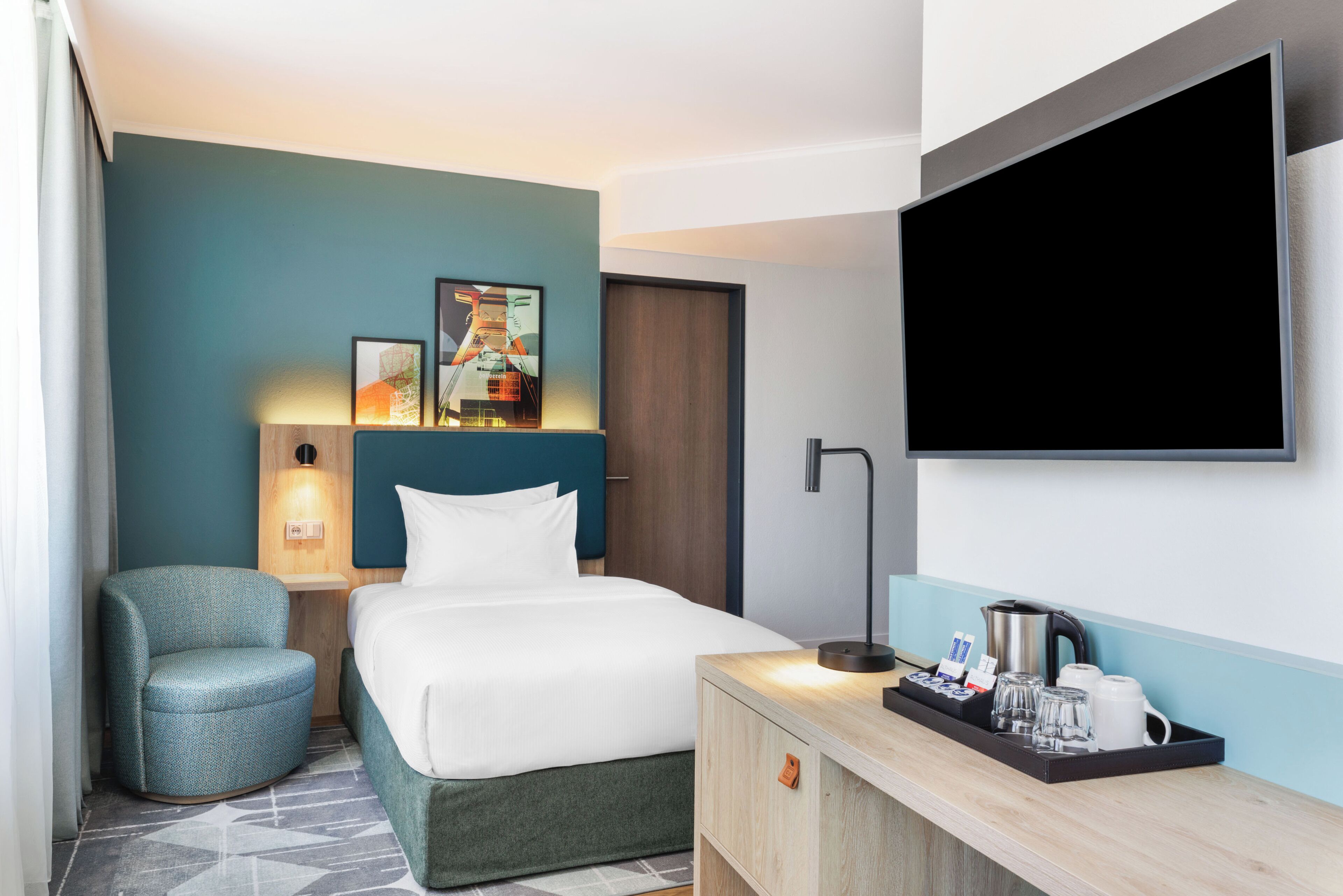 Ein Hotelzimmer mit einem Bett, einer Sitzecke, einem Schreibtisch mit Wasserkocher und einem Flachbildfernseher.