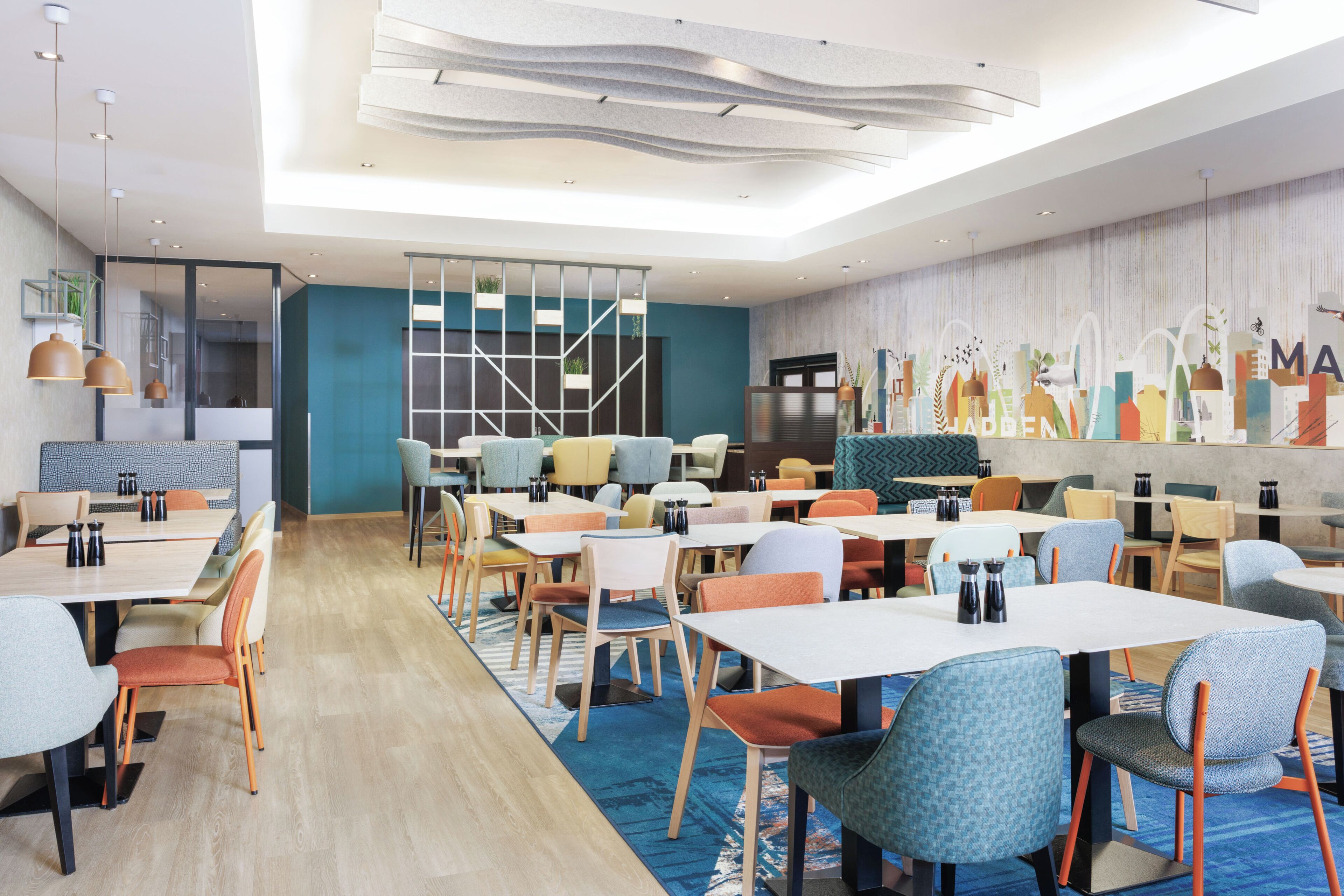 A modern dining area with multiple tables and chairs, a patterned ceiling, and a cityscape mural on the wall.