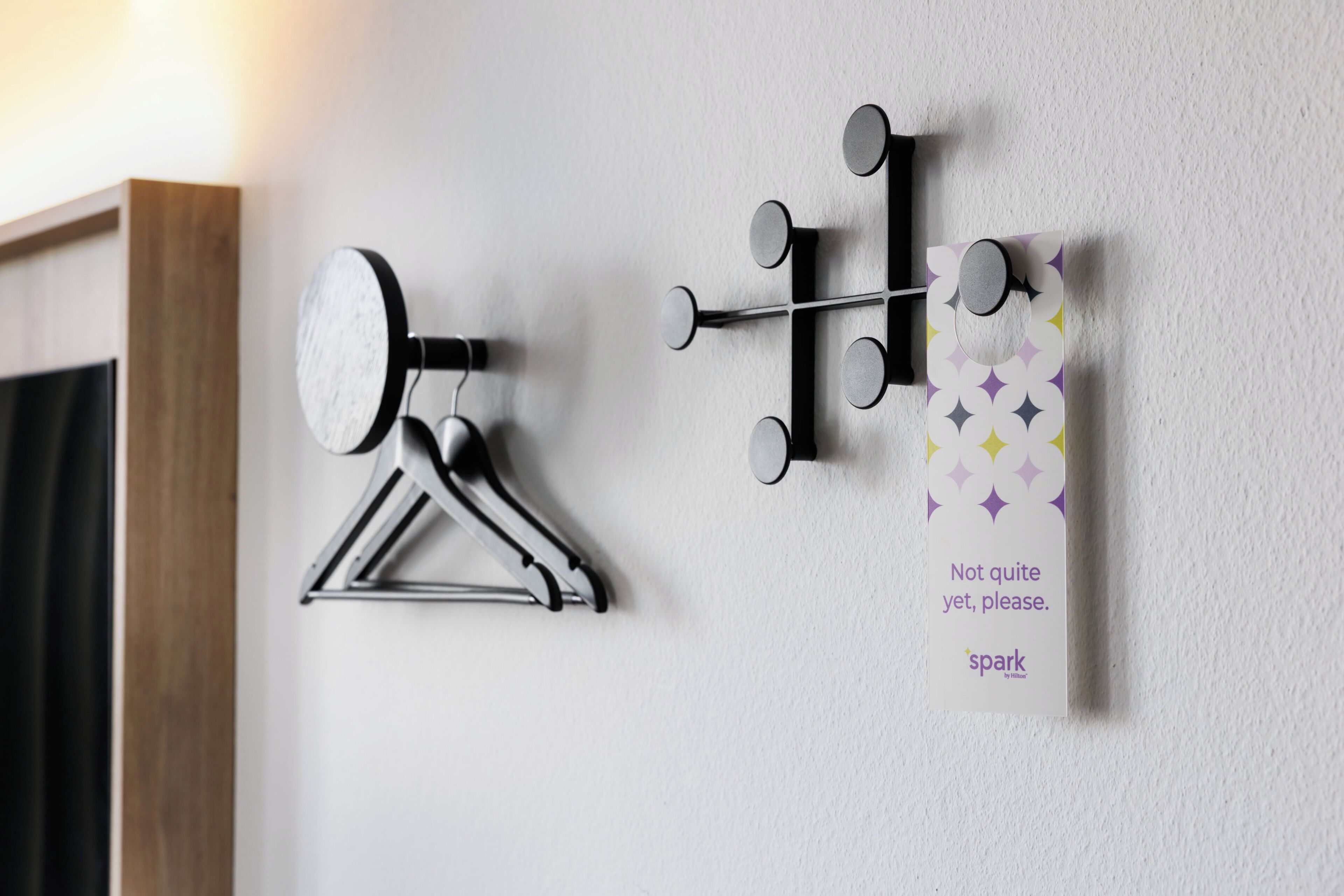A wall-mounted coat rack with a mirror and a decorative panel with a pattern and text.