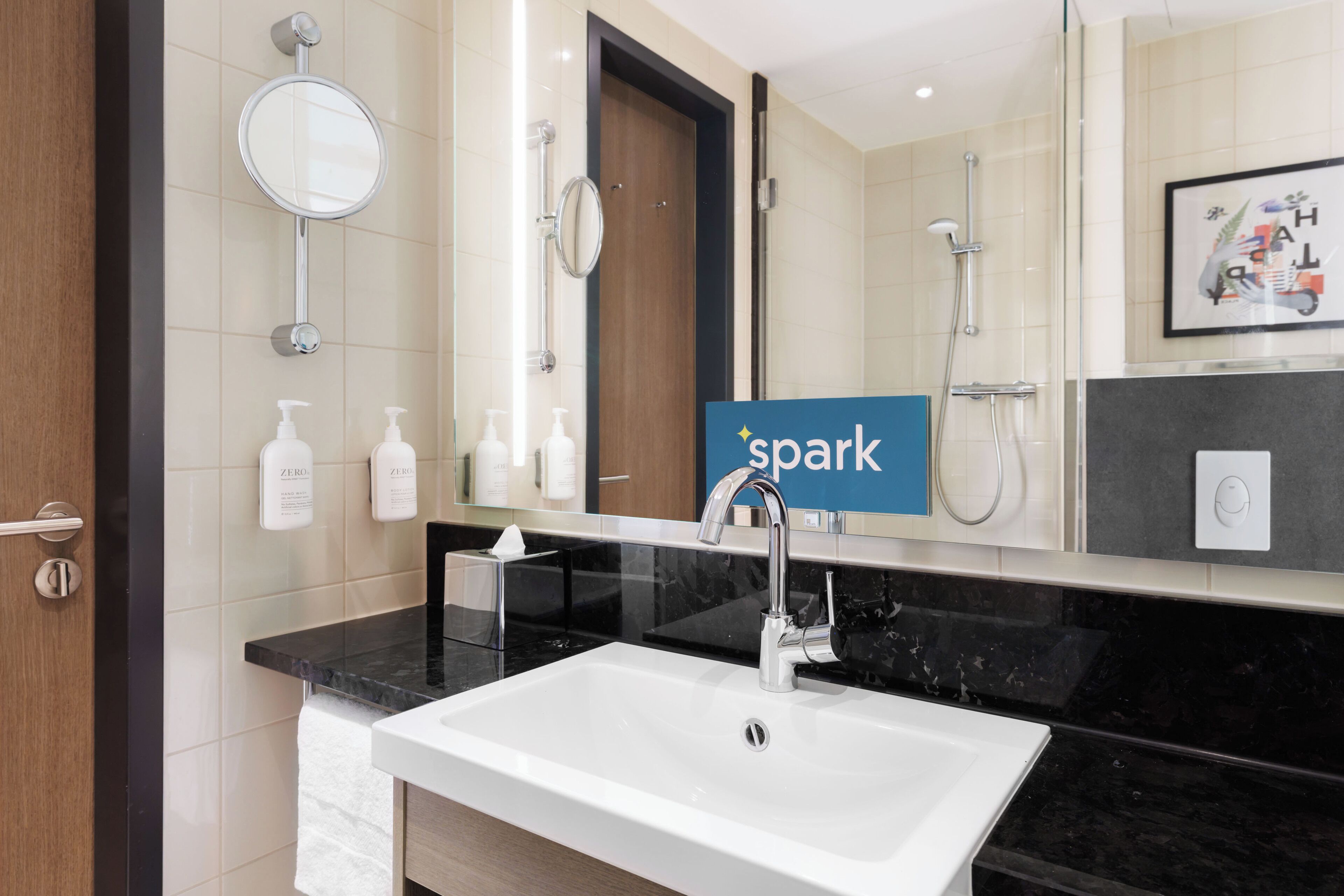 A modern bathroom with a white sink, a mirror, and a shower.