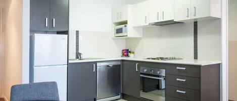 A compact kitchen with a refrigerator, dishwasher, oven, and microwave.